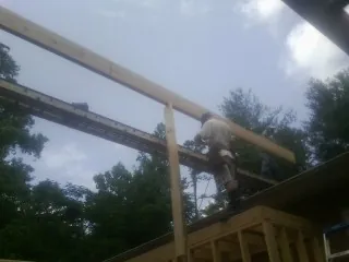 Carpenter setting a ridge beam over a new addition frame — Ice Dam Removal by Roofing Brothers in Sabillasville