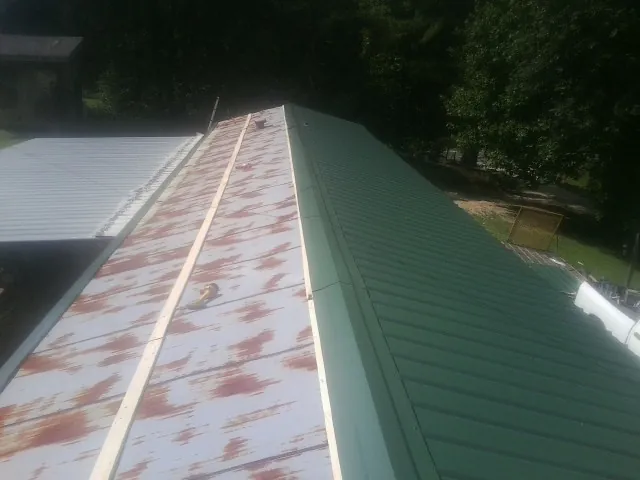 Old rusted panels beside newly installed green metal roofing — Wind Damage Roof Repair by Roofing Brothers in Sabillasville