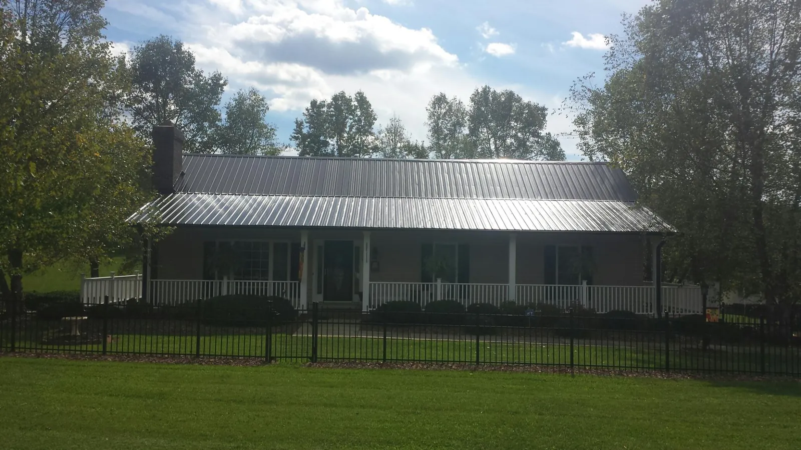 Gray metal roof on a brick ranch with a full width front porch — Gutter Guard Installation work by our crew in Sabillasville