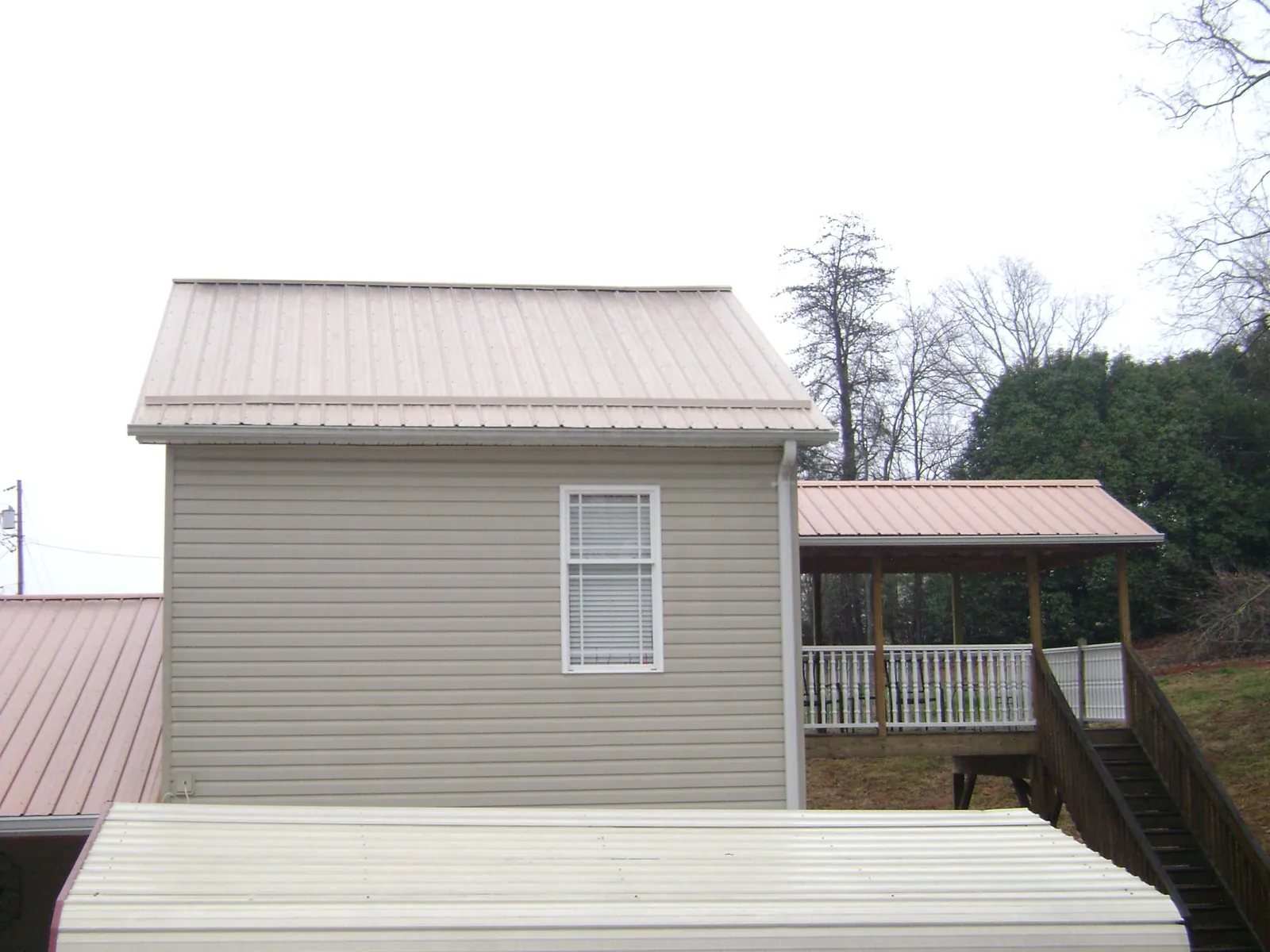 Tan metal roofs on a two story addition and attached porch, from a Roof Replacement job in Sabillasville