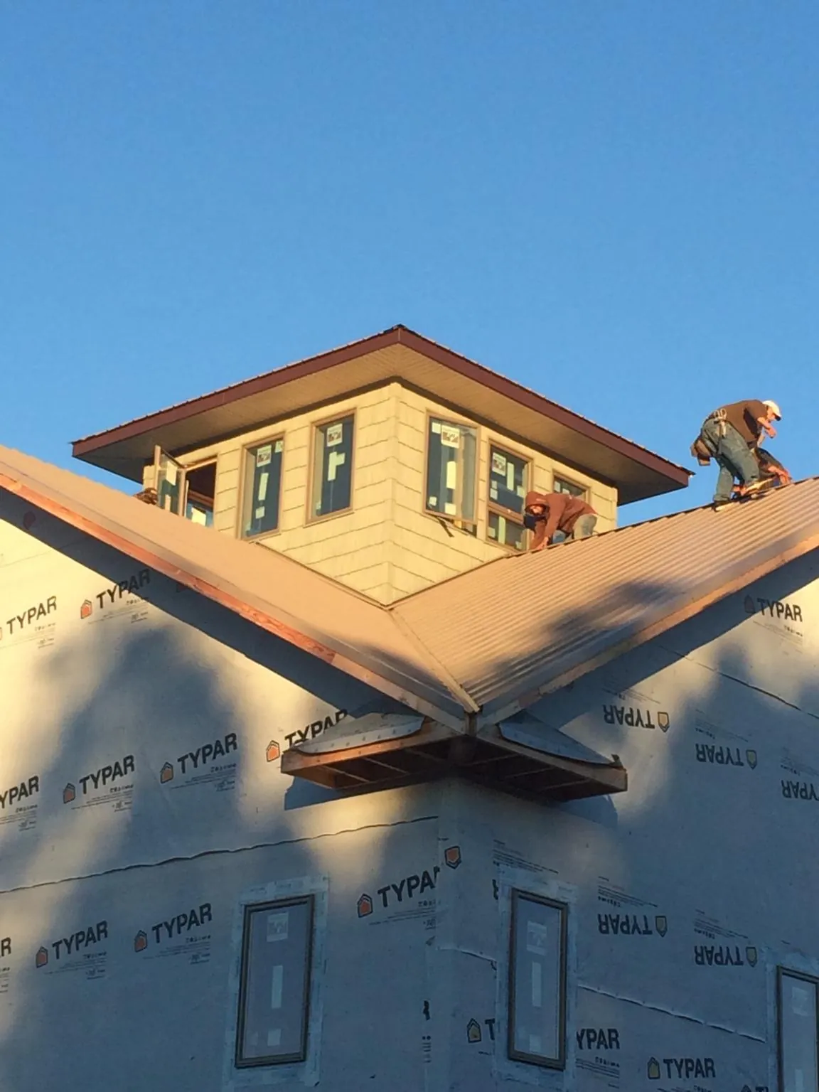 Roofers working around a rooftop cupola on a new metal roof at sunset — Roof Waterproofing in Sabillasville by Roofing Brothers